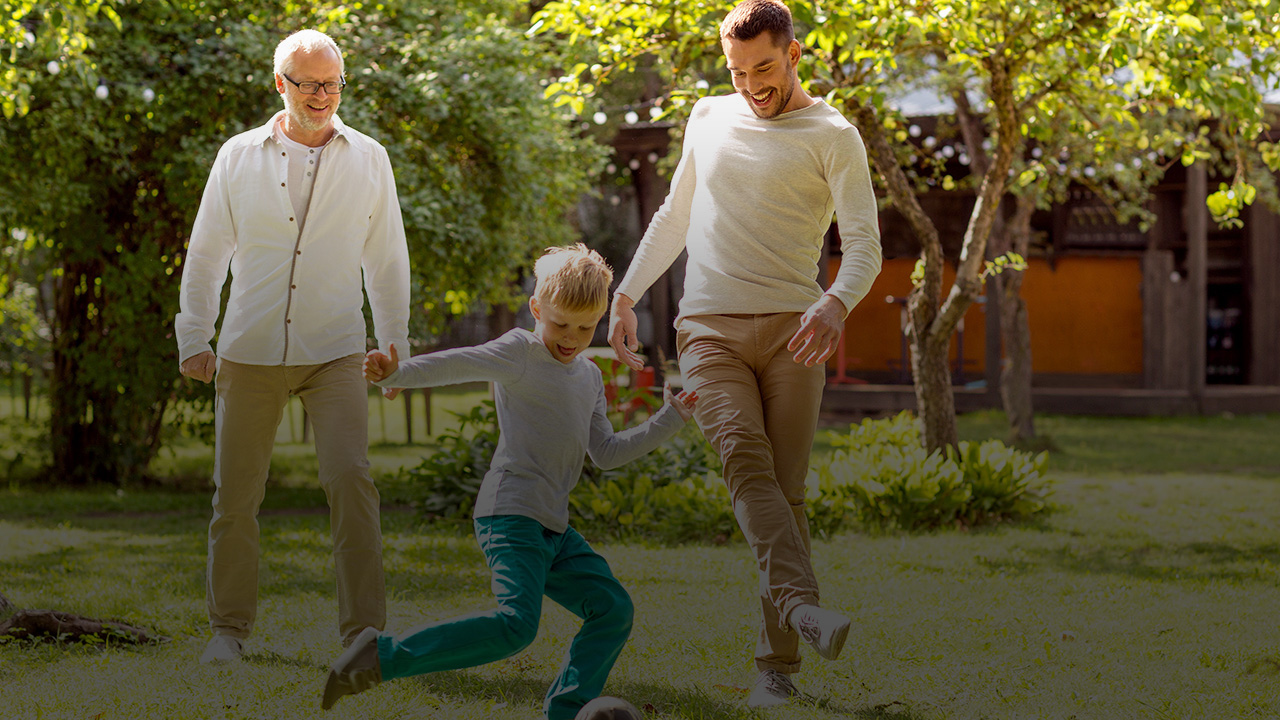 Ein Junge, ein jüngere Mann und ein ältere Mann spielen gemeinsam Fußball.